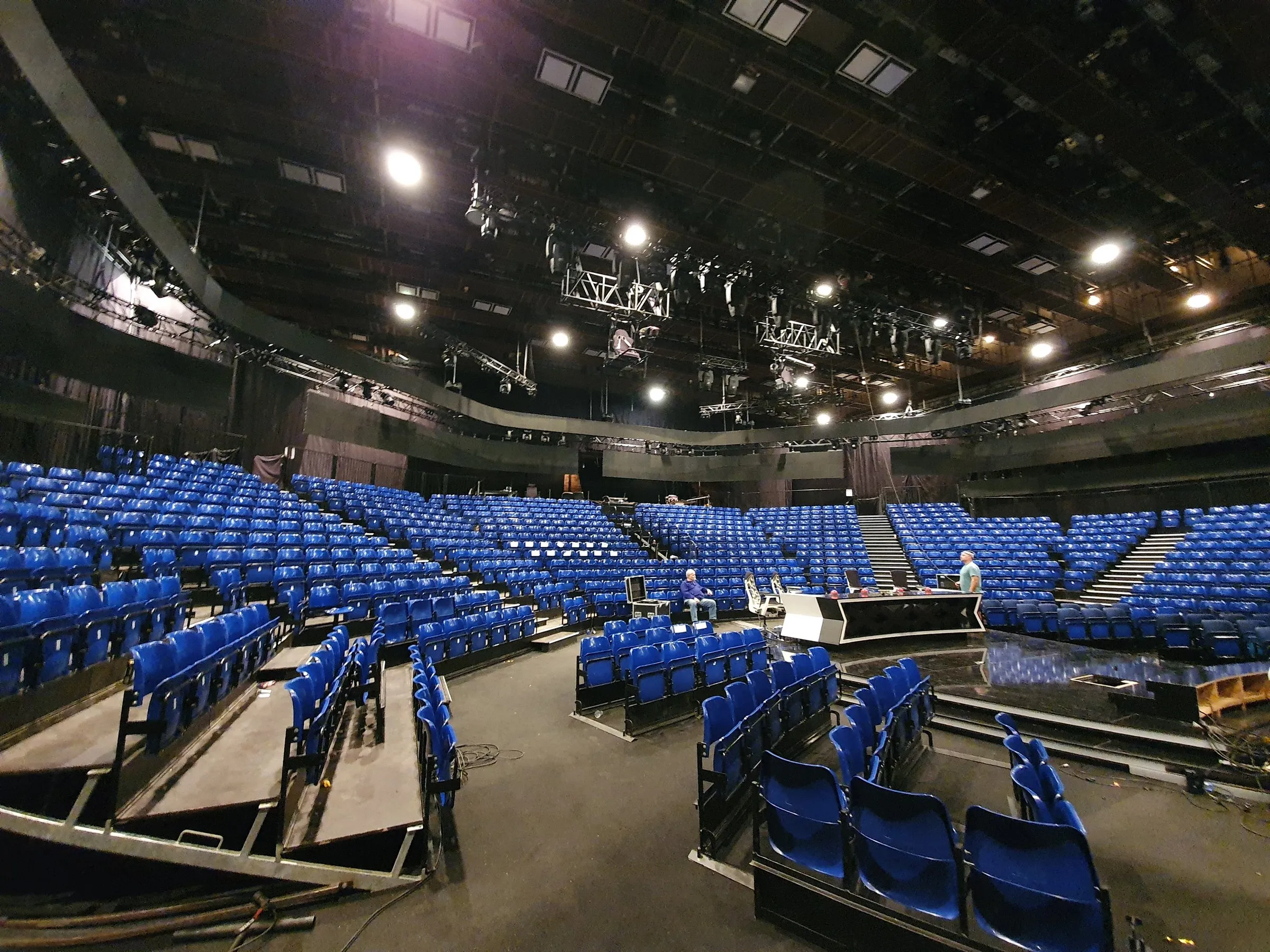 Arenaseats stand with blue tip-up seats around a stage